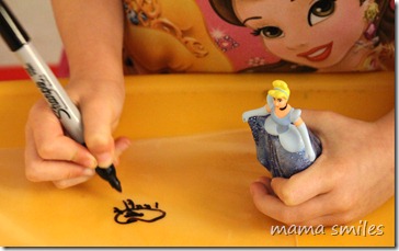 Emma decorating party bags with help from her Cinderella doll