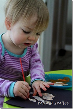 Lily paints with brush and fingers on black paper