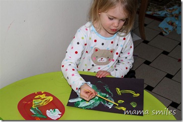 Emma experiments with paint on black paper