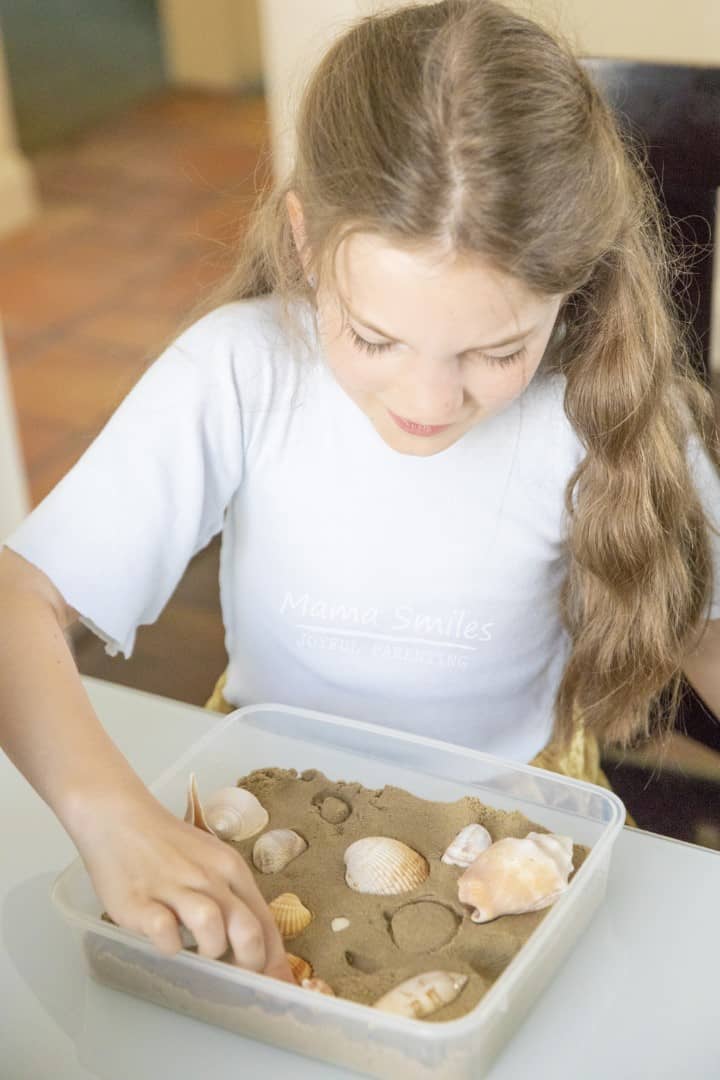 This simple kinetic sand seashell sensory bin makes a wonderful sensory play experience. It's also great for exploring different shapes and textures. #vbcforkids #sensoryplay #summeractivitiesforkids #summerfun #sensorybin #seashells #kineticsand